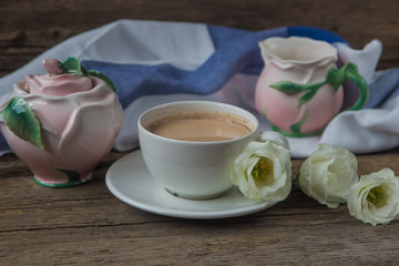 Cup of coffee with milk, red grapes, pink crockery and eustomas