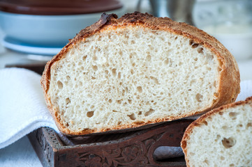 Homemade sourdough bread in a wooden tray on a wooden background