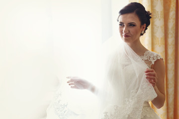 Radiant bride smiles while she holds veil in her hands