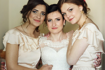 Beautiful bridesmaids in silk dresses hug bride tender