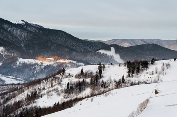 Fototapeta na wymiar Winter mountain view at dawn wooden fence in snow, blue, green t