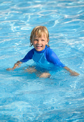 Fototapeta na wymiar Happy little boy has fun in swimming pool