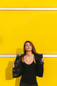 Young woman posing in front of a yellow wall