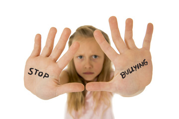 sweet and scared little schoolgirl showing the text stop bullying written in her hands