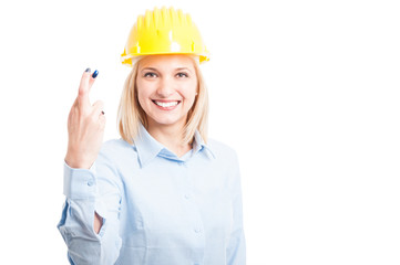 Female engineer wearing helmet showing fingers crossed