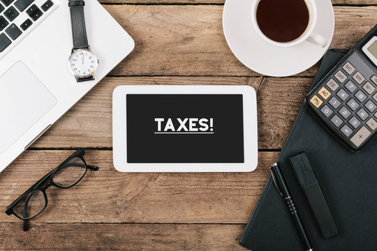 Taxes text on tablet computer on office desk