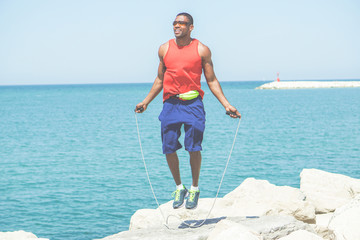 Afro american man jumping rope with sea view in background
