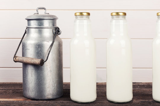 old milk can and bottles on wooden table