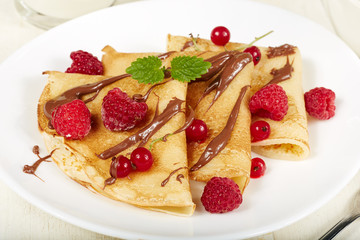 Pancakes with raspberry, red currant and chocolate. Dessert. Traditional Russian cuisine.