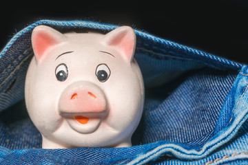 Pink piggy bank in a pocket of jeans