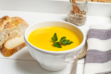 Sopa crema de calabaza zapallo en una bandeja blanca con rodajas de pan y cuchara. Vista superior