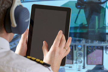 Airline pilot using tablet - obrazy, fototapety, plakaty