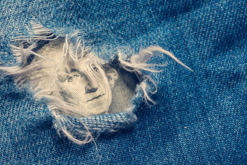 Dollar banknote in a hole of jeans