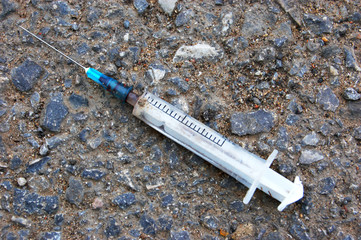 Used syringe with blood on the asphalt