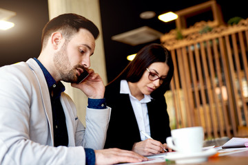 Business people at cafe bar solving problem. Talking on mobile phone.