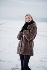Portrait of young elegance blonde girl in a fur coat background