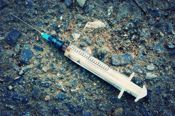 Used syringe with blood on the asphalt