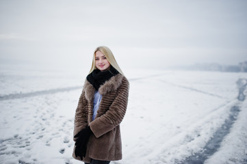 Portrait of young elegance blonde girl in a fur coat background