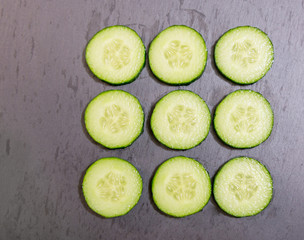 Sliced cucumbers on a dark stone background