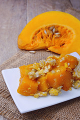 stir-fried pumpkin with eggs and fresh cut pumpkin on wooden background.