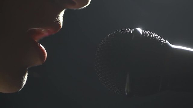 Close up footage of a woman singing to a microphone.