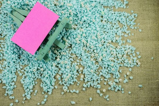 Blue easel with pink paper for inscriptions on the crumbled blue gravel.