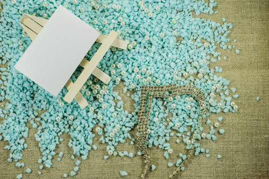 White easel with white paper for inscriptions with pearl beads and brilliant necklace.
