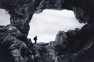 Surreal landscape with man exploring big cave