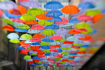 Fototapeta na wymiar Bright colorful umbrellas as street decoration hanging up in the open air. Photo taken with Lensbaby