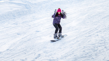 Fototapeta na wymiar girl snowboarder descends from the mountains in the snow on a snowboard