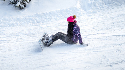 girl snowboarder fell and sitting on the snow