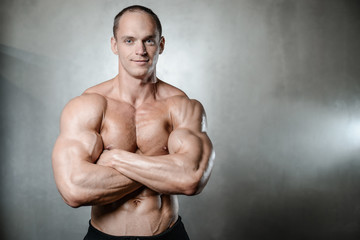 Fototapeta na wymiar Brutal strong bodybuilder man posing in studio on grey backgroun
