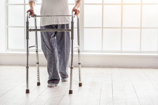 Old Woman Holding Foldable Walker And Moving In Hospital