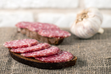 salami sausage sliced with bread on burlap