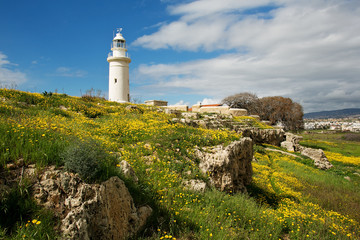 Fototapeta na wymiar White lighthouse over the yellow flowered meadow