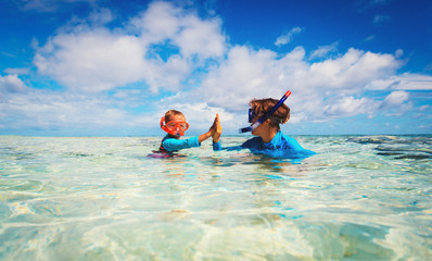 happy mother and son snorkeling on beach
