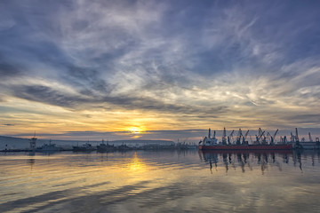 Obraz premium Landscape of ship and cranes in port at sunset.