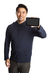 Attractive man wearing a blue hooded shirt, standing against a white background holding and showing a digital reader. Toothy smile.