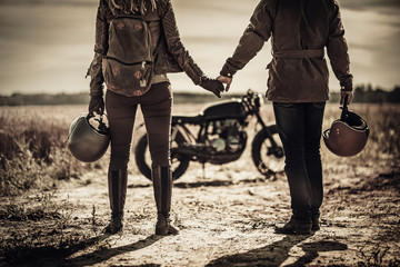 Jeune couple de café racer élégant et motos personnalisées vintage dans le champ