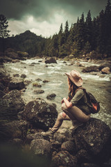 Beautiful woman hiker near wild mountain river
