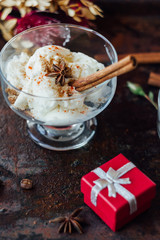White ice cream with cinnamon and star anise on black rustic board.
