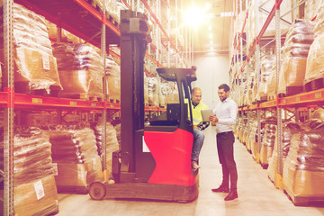 men with tablet pc and forklift at warehouse