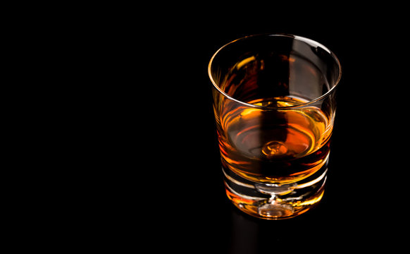 Glass of whiskey isolated on black background