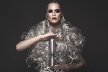 Beautiful girl in art dress and avant-garde hairstyles with cosmetic products in her hands. Beauty...