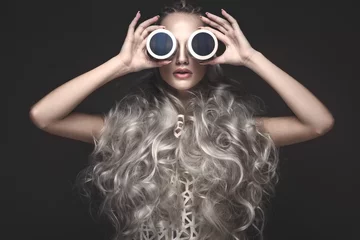 Schönes Mädchen in Kunstkleidung und Avantgarde-Frisuren mit kosmetischen Produkten in ihren Händen. Schönes Gesicht. Fotos im Studio aufgenommen. © Kobrinphoto