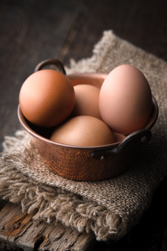 Chicken eggs in the cooper pot on the wooden table