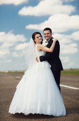 Fototapeta na wymiar beautiful and young newlyweds standing together on the road