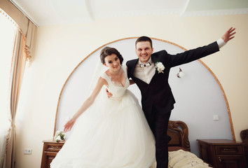 young and happy bride and groom standing at home