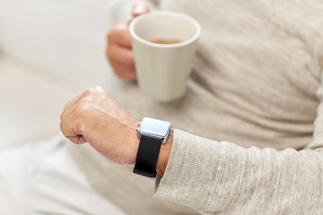 close up of senior man with tea and wristwatch