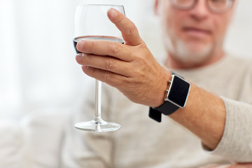 senior man drinking red wine from glass at home